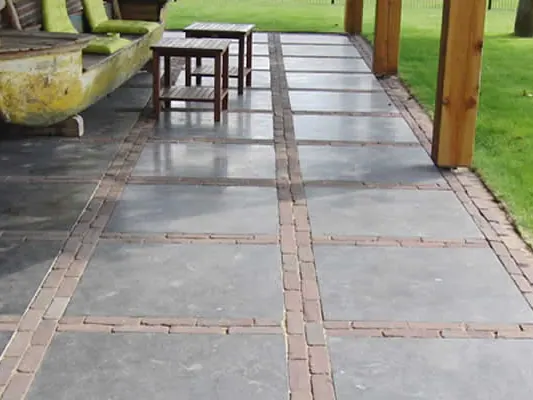 Aangelegd terras van natuursteen met pergola en beplanting
