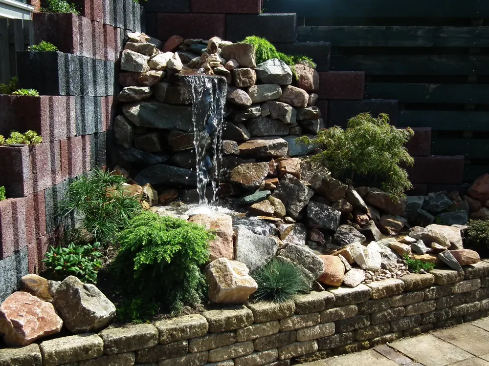 Vijver met waterval van natuursteen en beplanting