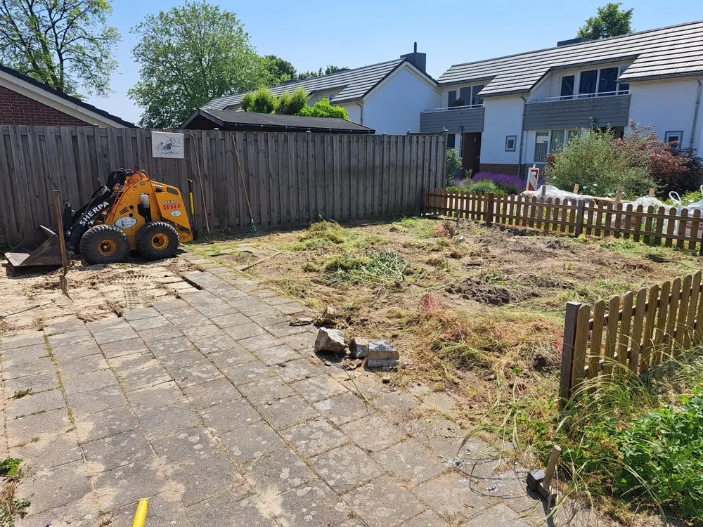 Achtertuin tijdens de aanleg, met machine en uitgezet grondwerk