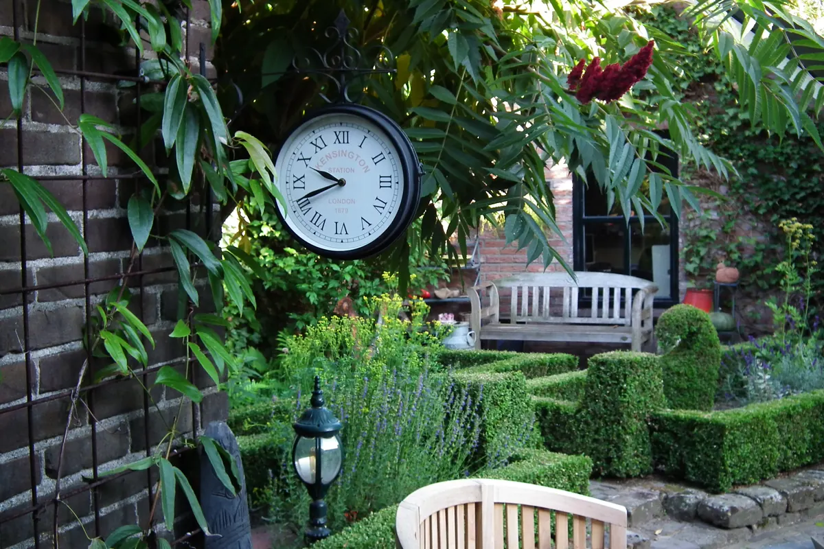 Beschutte zithoek met hagen en een bank in een verzorgde tuin