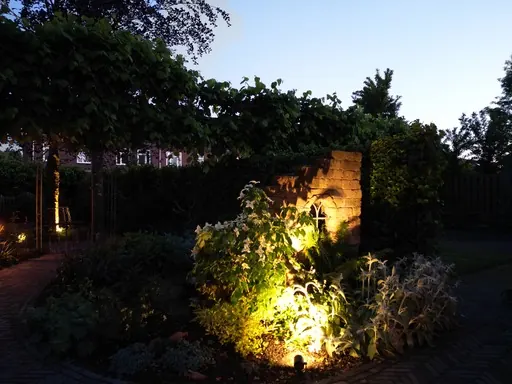 Verlichte folly van oude bakstenen in een avondtuin